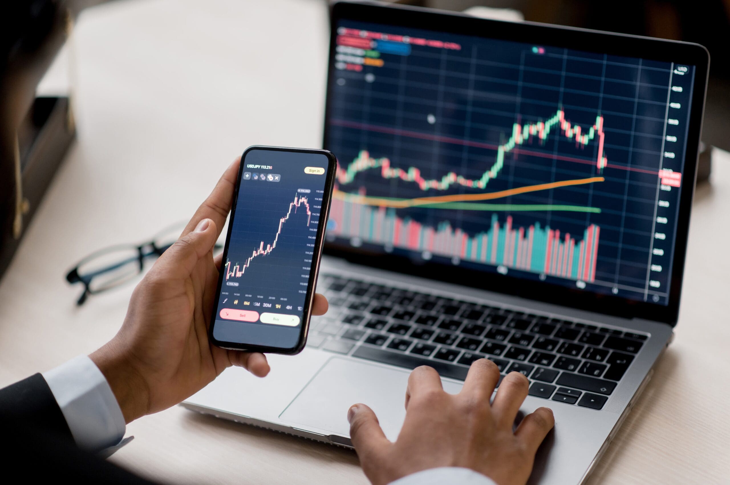 person looking at chart on laptop and phone