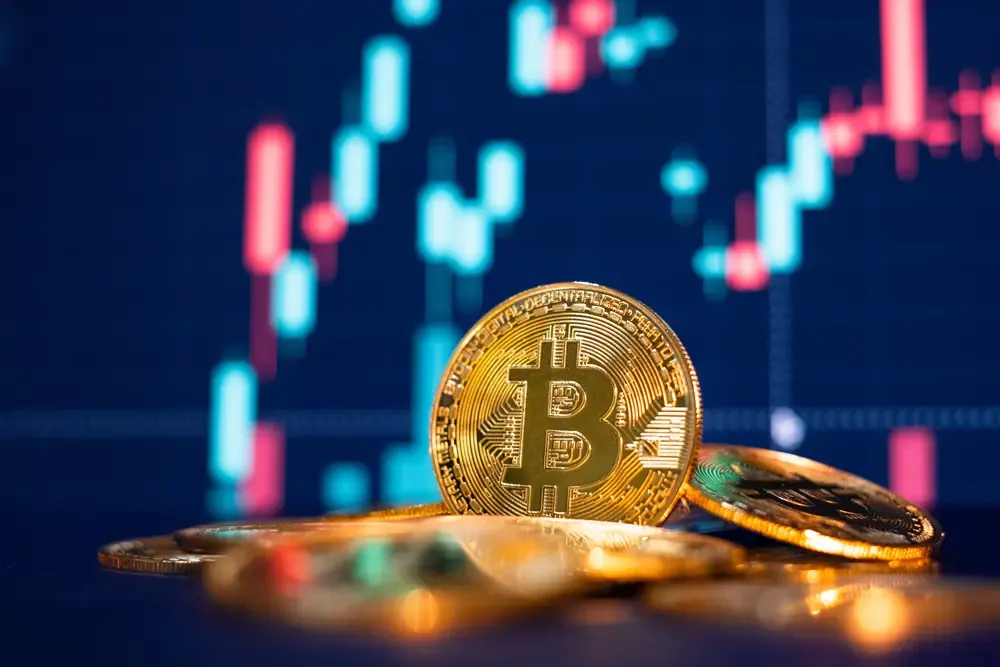 Moneda de bitcóin frente a un gráfico financiero